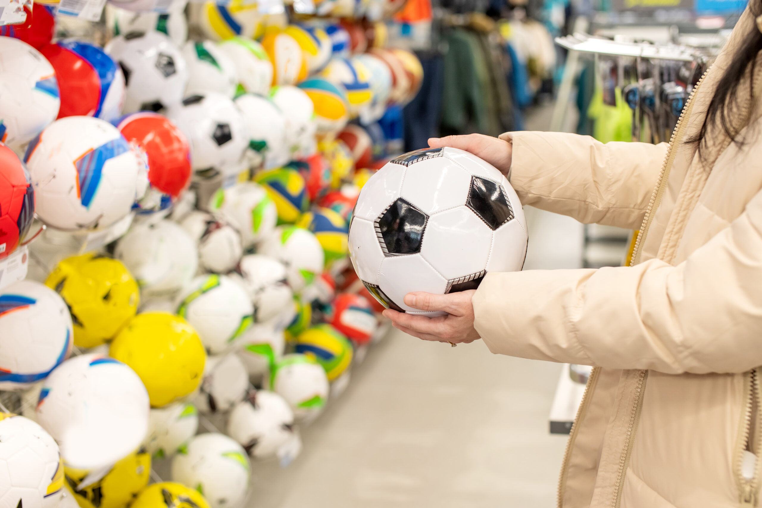 Persona eligiendo un balón de fútbol en una tienda