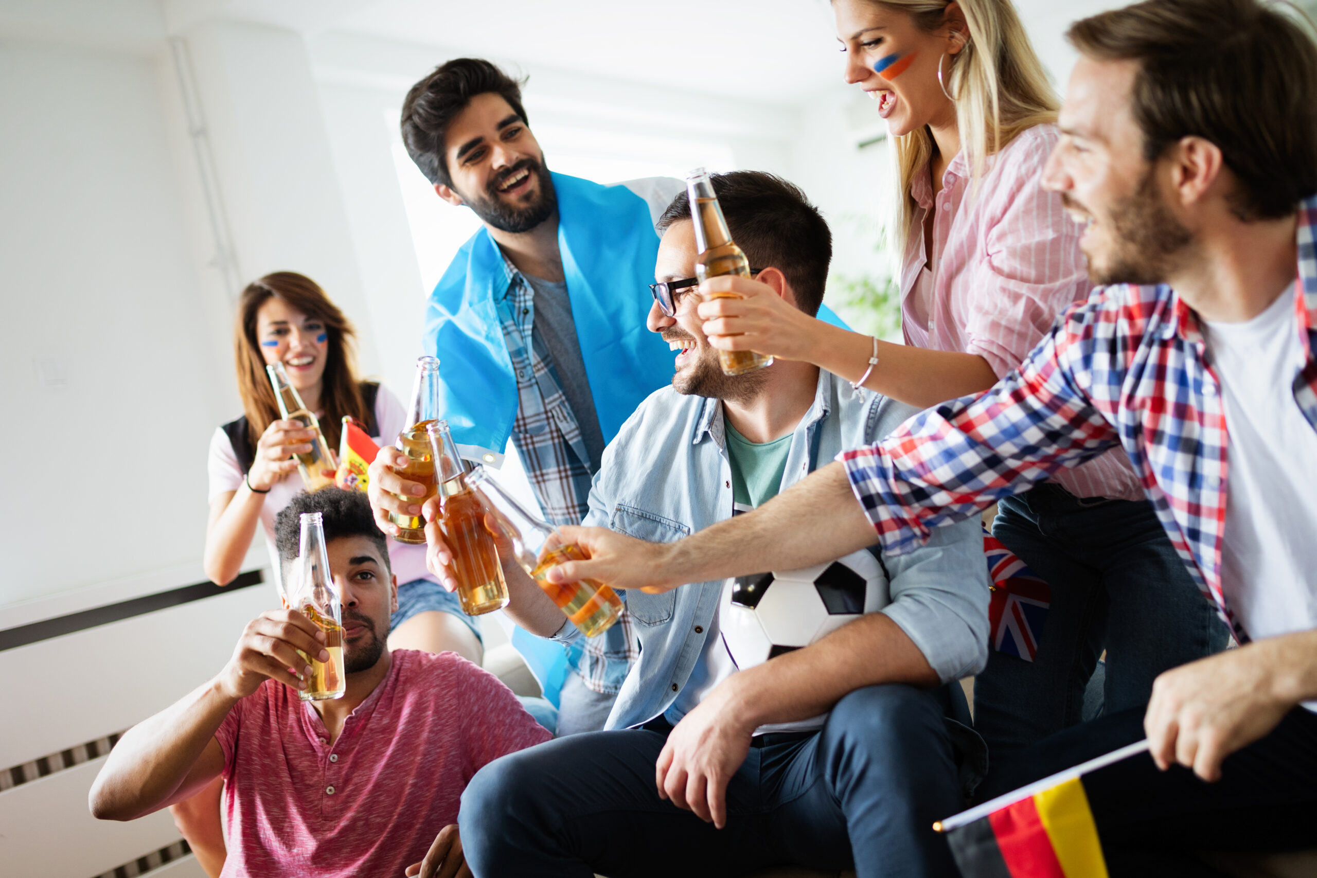 Young happy group of friends watching sport on television and cheering